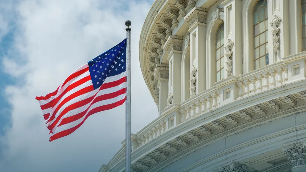 United States flag flying in front of the Capitol dome