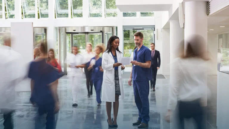 Clinician and nurse reviewing a document in a busy hospital lobby