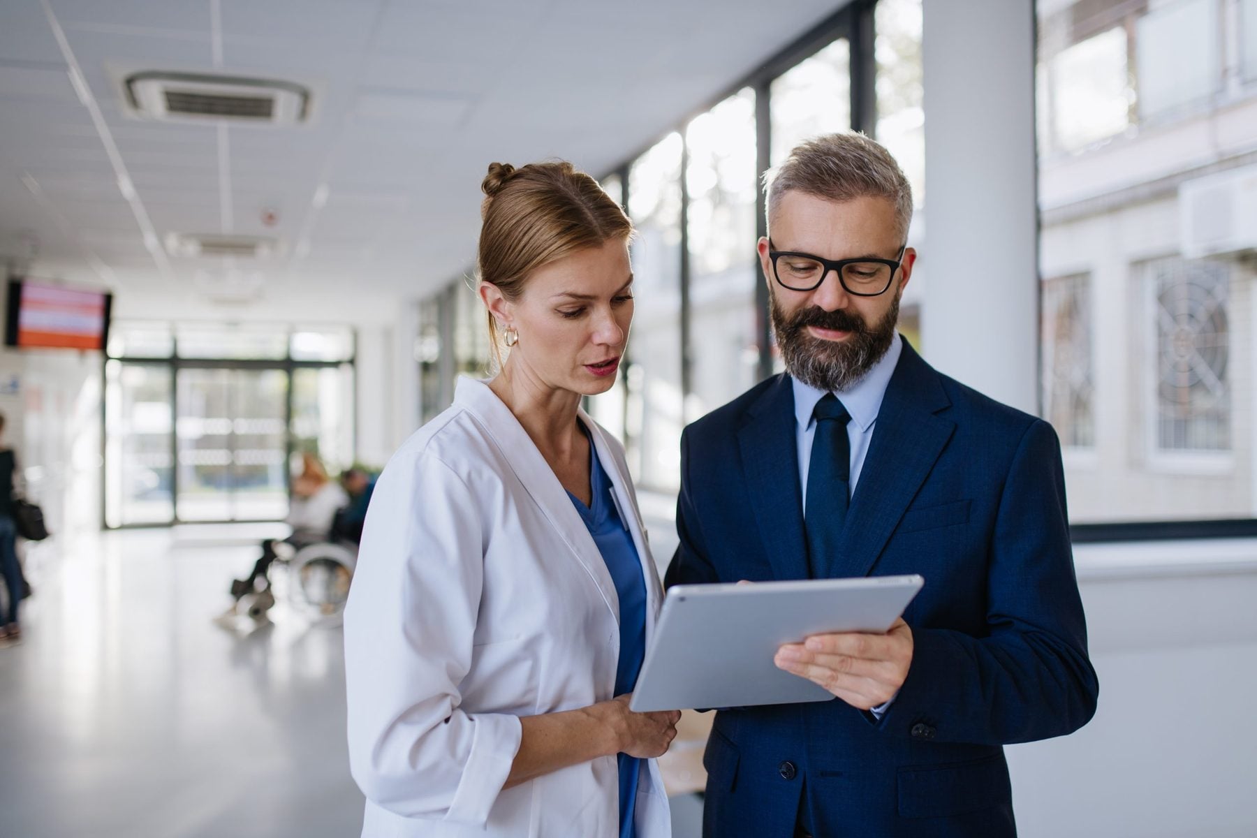 Compliance lead and clinician reviewing a practitioner record on a tablet
