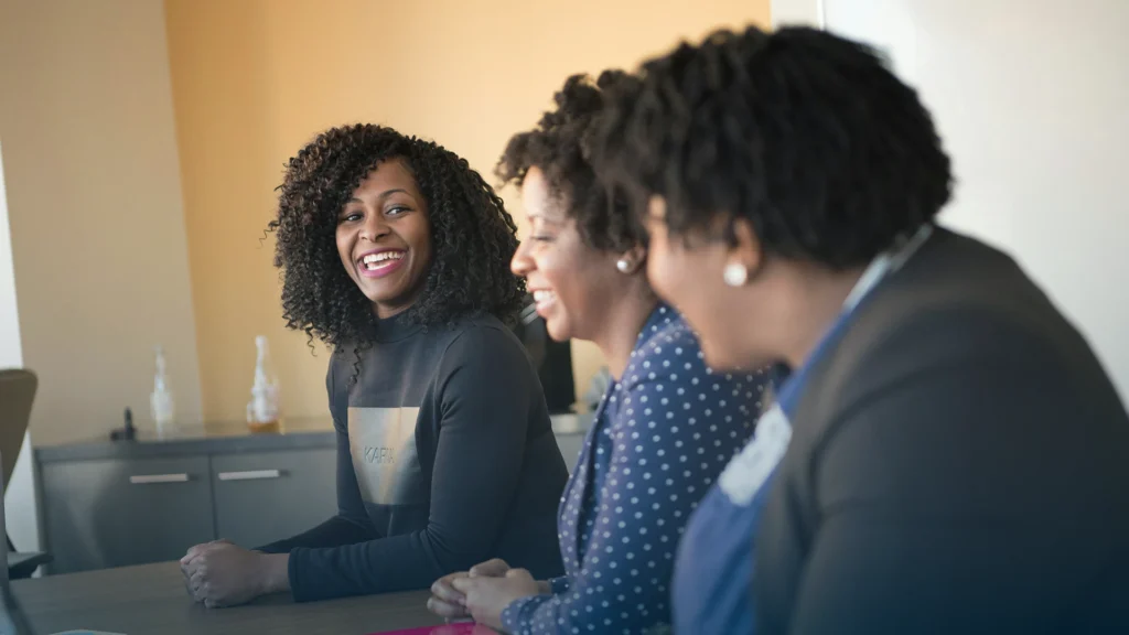Three colleagues laughing together at a conference table