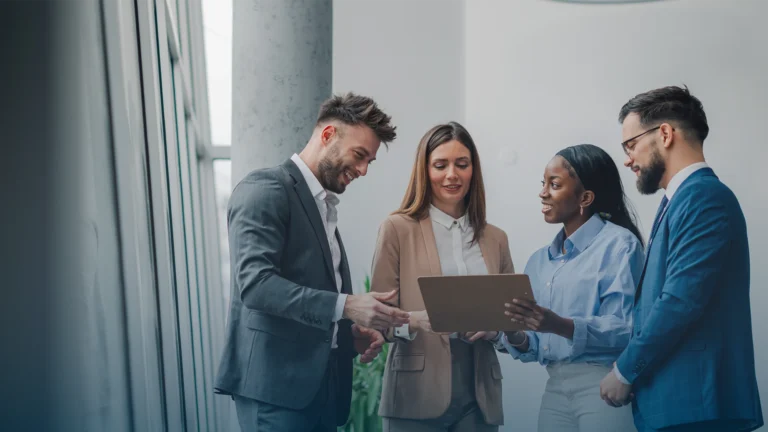 Four colleagues reviewing a clipboard together in a bright office