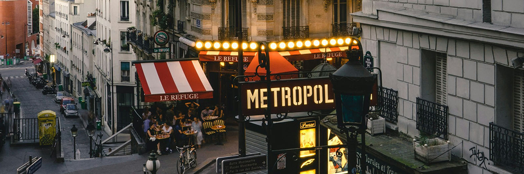 European street corner with cafe awnings and a lit Metropol sign