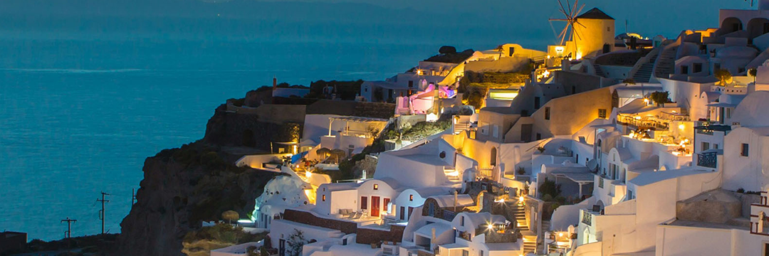 Whitewashed village on a cliff above the sea at dusk in Greece