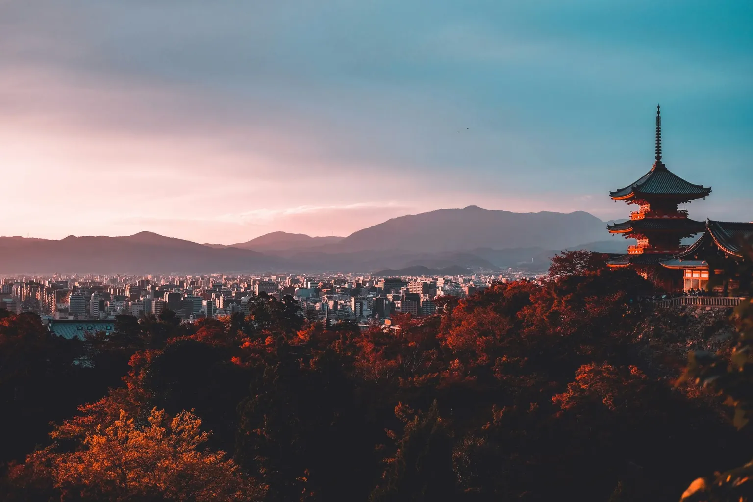 Pagoda above a city and mountains at sunset in Japan