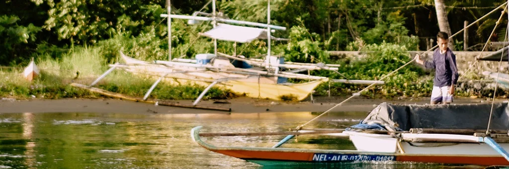 Outrigger boats moored along a riverbank in the Philippines