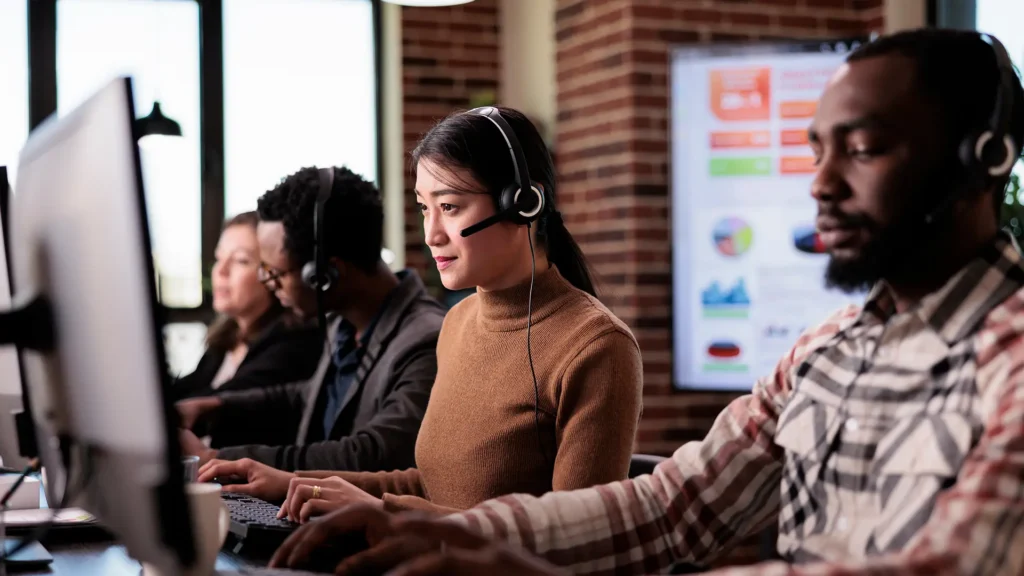 Call center verification agents with headsets working at monitors in an office