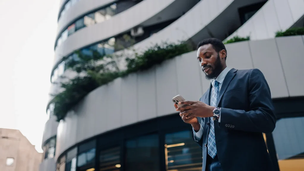 Compliance executive checking his phone outside a modern office building