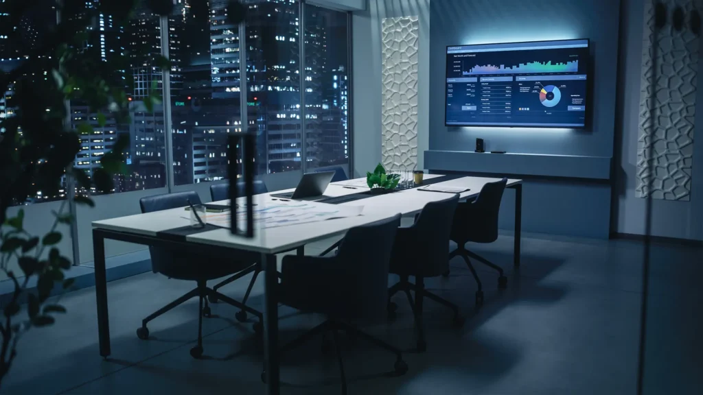 Conference room with a business dashboard on the wall screen and city lights beyond the windows