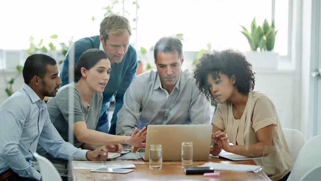 Small commercial team gathered around a laptop in a bright office