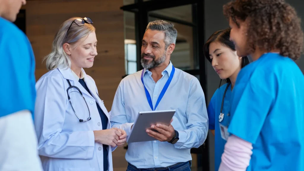 Field representative sharing information on a tablet with a group of clinicians
